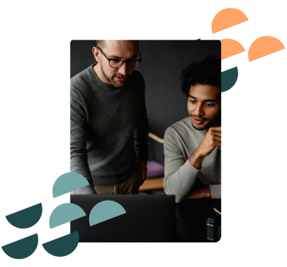 Two men talking while looking at laptop